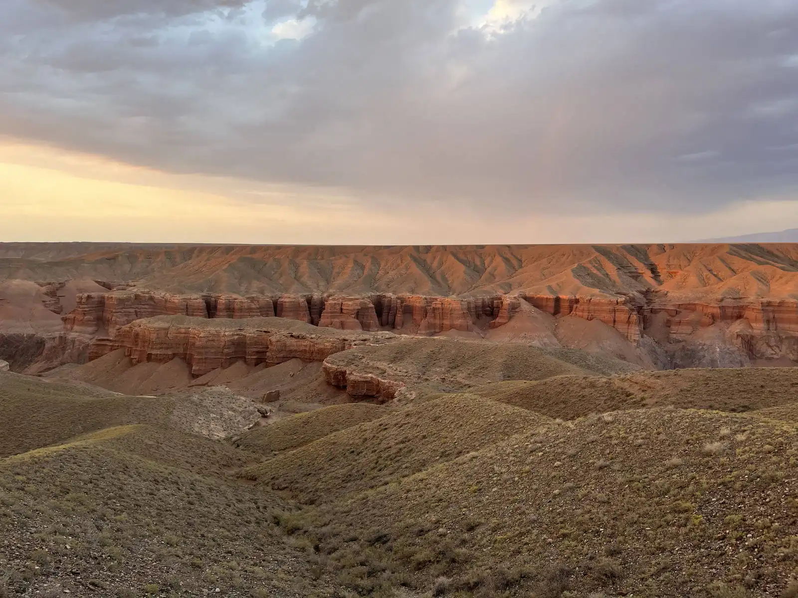 Wide view of Charyn Canyon's eroded cliff edge under a moody evening sky